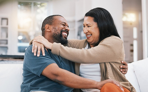 Happy, hug and mature couple on sofa in living room for bonding, healthy relationship and marriage. Love, home and happy black man and woman embrace on couch for relaxing, happiness and commitment