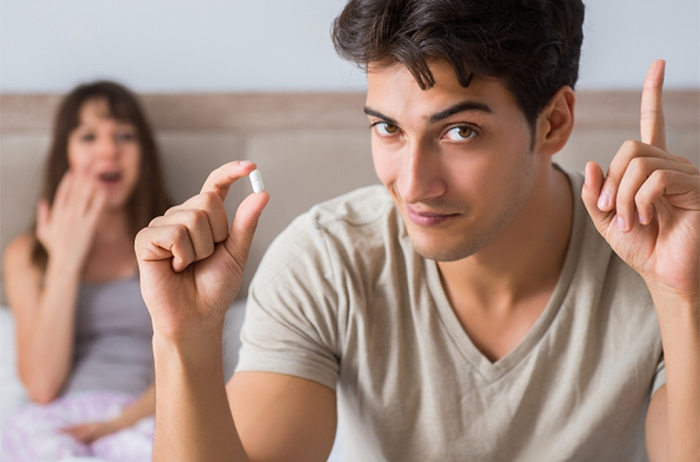 Boyfriend sitting on edge of bed about to take Stamina for Men instant erection pill